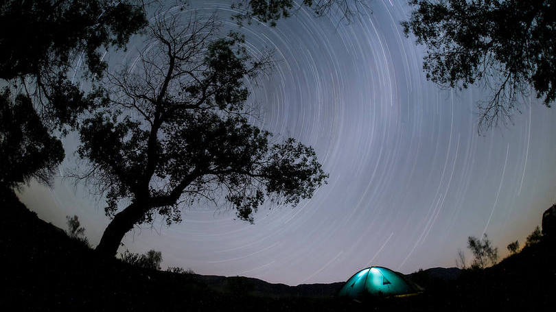 Foto de alta exposição mostra o rastro deixados pelas estrelas no céu. Essa imagem foi registrada na área de camping do Parque Nacional Altyn-Amel, que fica na região de Almaty, Cazaquistão. 