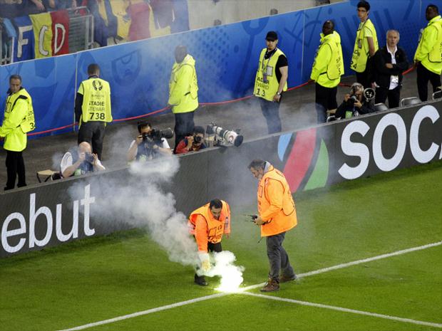 Funcionários retiram sinalizadores que foram atirados no gramado durante a partida entre Albânia e Romênia