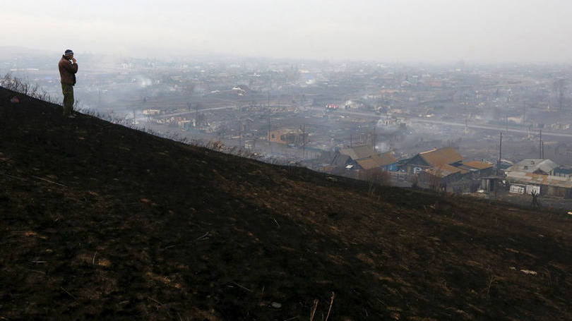 Homem observa incêndio no sul da Sibéria