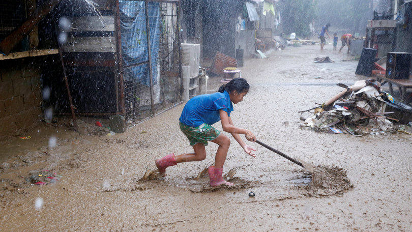 Inundações: filipina tenta remover a lama de casa após enchente