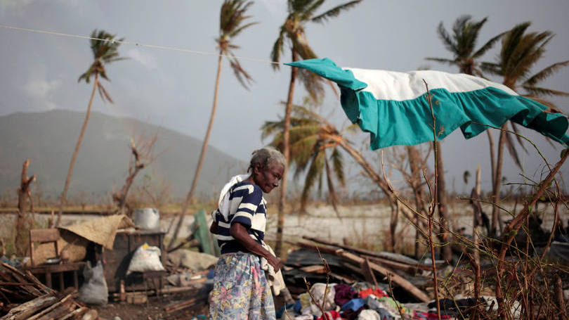 Mulher no meio da destruição deixada pela passagem do furacão Matthew no Haiti